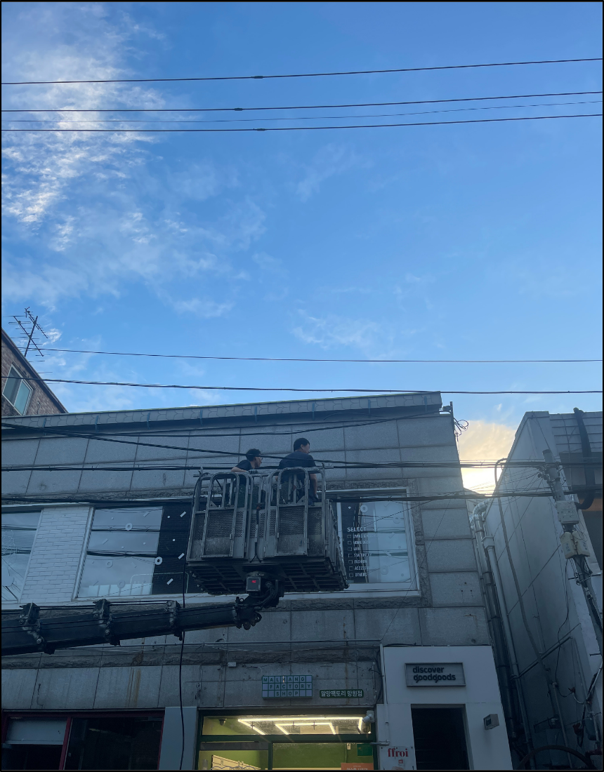 마포 망원동 상가 외벽에서 고소작업장비를 이용해 외선 경로를 확인하는 전기공사 현장